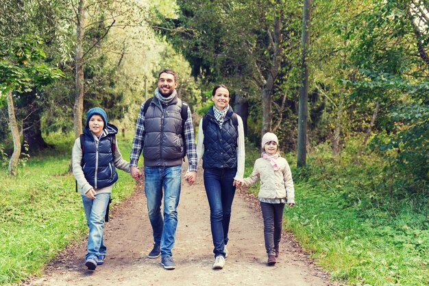 avontuur, reizen, toerisme, wandelen en mensenconcept - gelukkig gezin wandelen met rugzakken in het bos