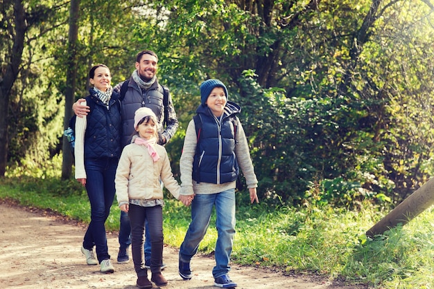 avontuur, reizen, toerisme, wandelen en mensenconcept - gelukkig gezin wandelen met rugzakken in het bos