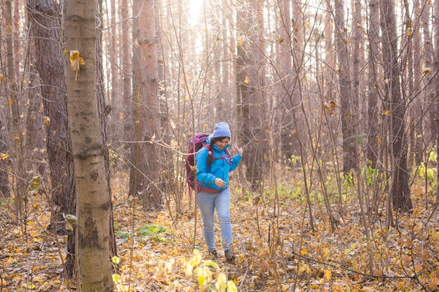 Avontuur, reizen, toerisme, wandeling en mensenconcept - glimlachende vrouw die met rugzakken over herfst natuurlijke achtergrond loopt.