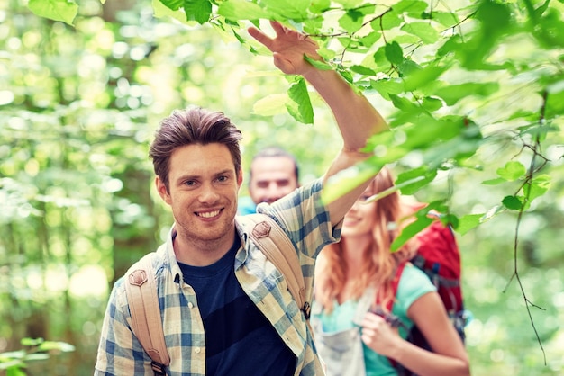 avontuur, reizen, toerisme, wandeling en mensenconcept - groep lachende vrienden die met rugzakken in het bos lopen