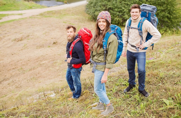 avontuur, reizen, toerisme, wandeling en mensenconcept - groep lachende vrienden met rugzakken buitenshuis