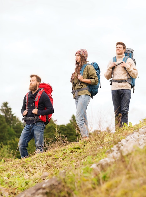 avontuur, reizen, toerisme, wandeling en mensenconcept - groep lachende vrienden met rugzakken buitenshuis