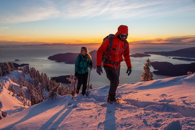 Avontuur zoekende man en vrouw wandelen naar de top van een berg tijdens zonsondergang in de winter