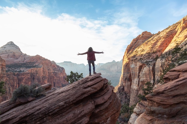 Avontuurlijk meisje aan de rand van een klif kijkt naar een canyonlandschap Utah