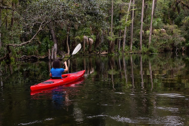 Avontuurlijk meisje kajakken op een rivier bedekt met bomen