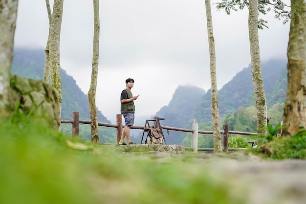Foto avontuurlijke aziatische man die alleen staat met telefoon
