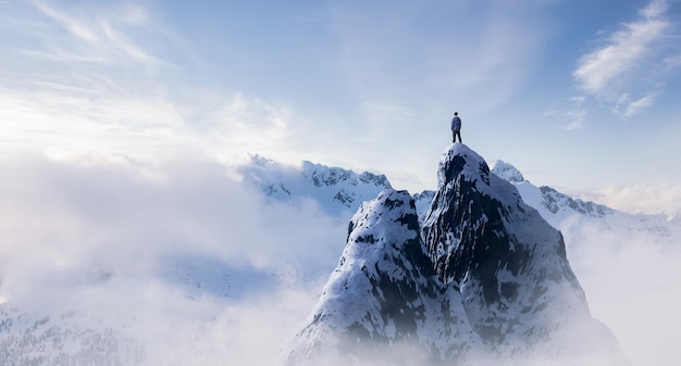 Avontuurlijke Man Wandelaar staande op de top van ijzige piek met rotsachtige bergen op de achtergrond
