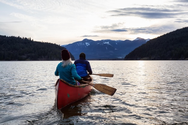 Avontuurlijke mensen op een houten kano genieten van het Canadese berglandschap