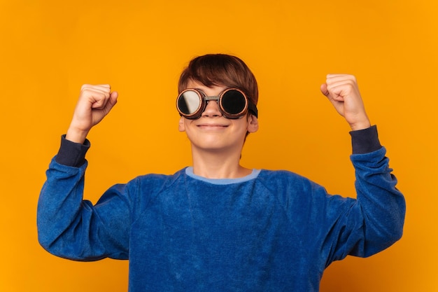 Avontuurlijke tienerjongen maakt het winnaarsgebaar terwijl hij een pilotenbril draagt