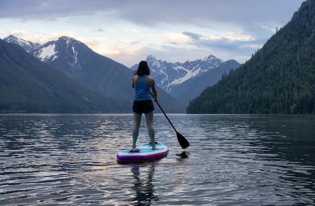 Avontuurlijke vrouw paddleboarden in een meer rond het Canadese berglandschap