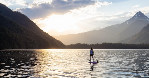 Avontuurlijke vrouw paddleboarden in een meer rond het Canadese berglandschap