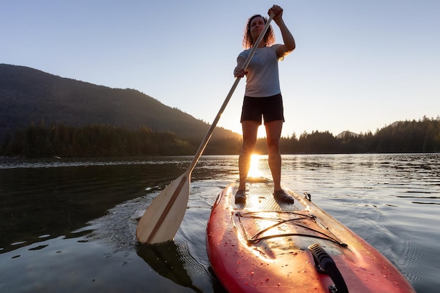 Avontuurlijke vrouw peddelend op een paddleboard in een vredig meer