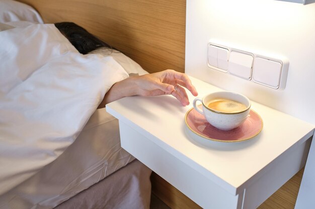 Awake anonymous woman reaching out cup at bedside