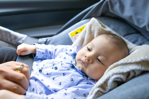 写真 自動車シートに横たわっている目覚めた赤ちゃん