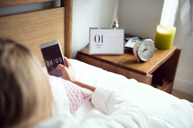 Photo an awake woman checking her mobile phone