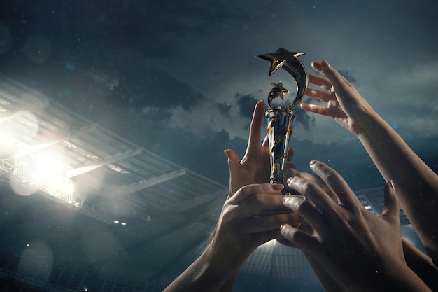 Photo award of victory, male hands tightening the cup of winners against cloudy dark sky