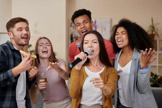 Awesome home party attractive young asian girl holding microphone and singing while playing karaoke