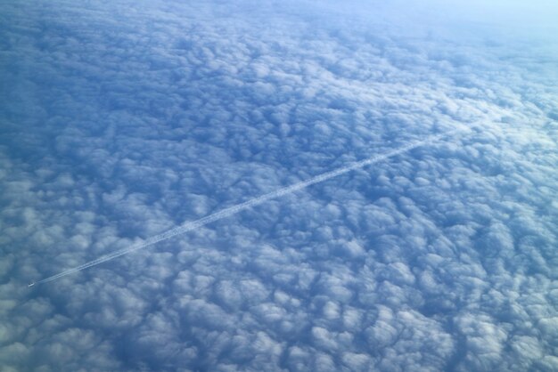 Awesome view of a jet plane flying against the sea of clouds seen from airplane during the flight