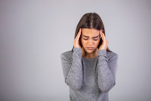 Photo awful headache oman holding head in hands and keeping eyes closed while standing against grey background