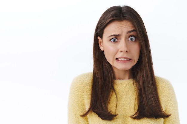 Awkward and embarrassed cute brunette girl feel concerned and anxious about something she did wrong