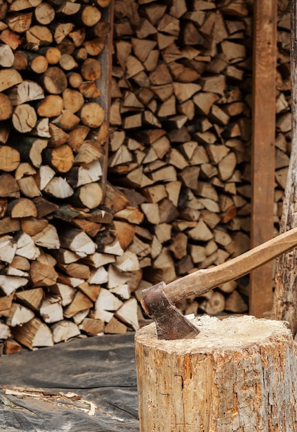 The AX sticks out in the stump In the background beautifully stacked firewood for kindling the stove