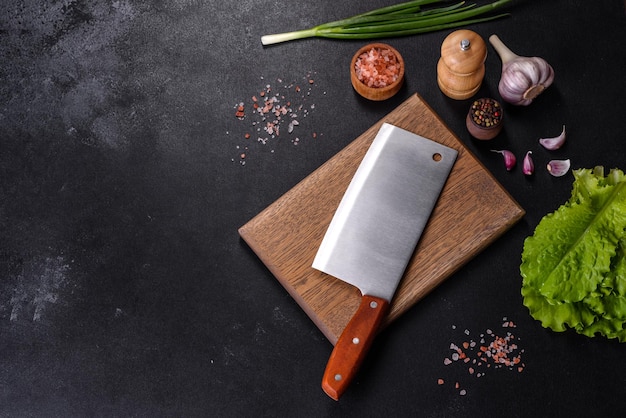 An axe for meat spices and herbs a cutting board against a dark concrete background