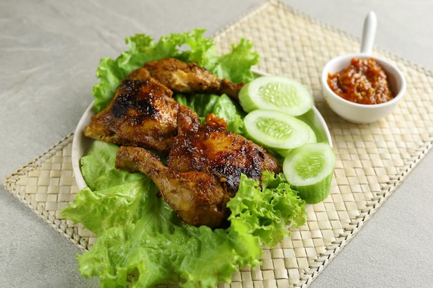 Ayam Bakar Indonesian traditional chargrilled chicken Arranged on white plate lined with lettuce