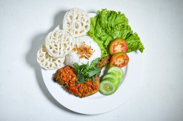 Ayam geprek indonesian food or geprek chicken with sambal hot chili sauce served rice on white plate