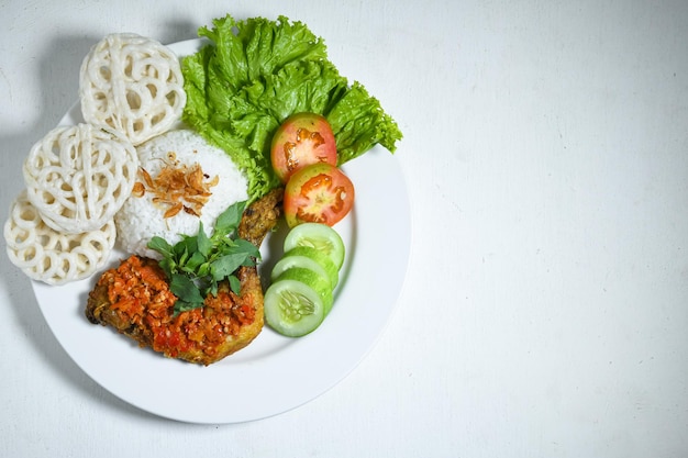 Индонезийская еда аям гепрек или курица гепрек с острым соусом чили самбал, подается рис на белой тарелке