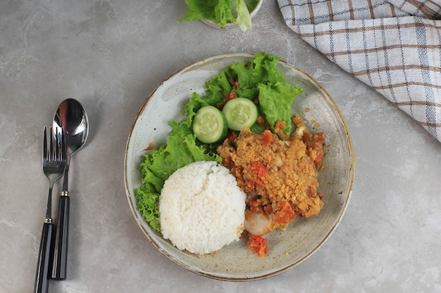Ayam Geprek is populair straatvoedsel in Indonesië. Gemaakt van Krokante Kip Smashed in Sambal Bawang (Chili Knoflooksaus). Geserveerd met Rijst en Groente