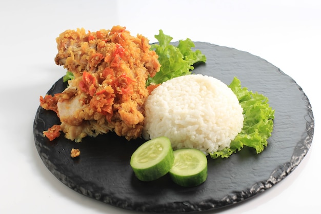 Photo ayam geprek is popular street food in indonesia. made from crispy chicken smashed in sambal bawang (chilli garlic sauce) . served with rice and vegetable