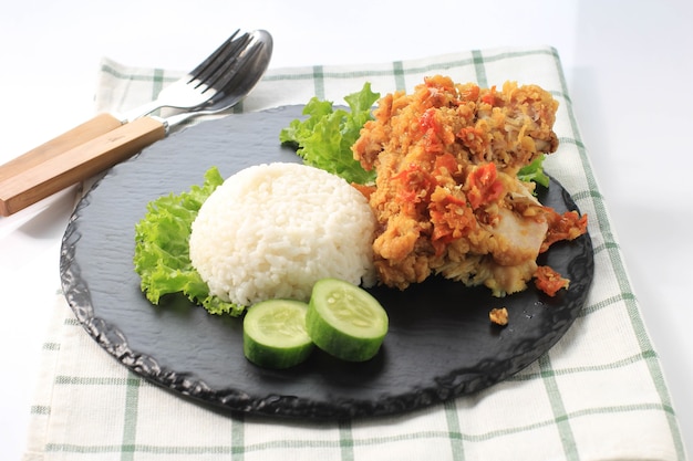 Photo ayam geprek is popular street food in indonesia. made from crispy chicken smashed in sambal bawang (chilli garlic sauce) . served with rice and vegetable