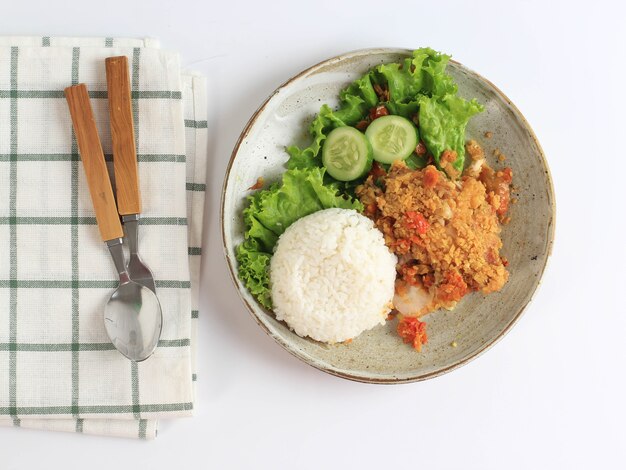 Photo ayam geprek is popular street food in indonesia. made from crispy chicken smashed in sambal bawang (chilli garlic sauce) . served with rice and vegetable