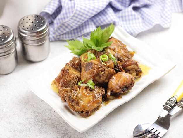 ayam goreng mentega or fried chicken with soy sauce butter and onion served on white plate