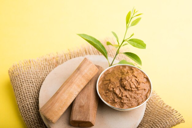 Photo ayurvedic chandan or sandalwood paste in silver bowl with sticksand leaves placed over sahanor sahana or circular stone base for creating paste