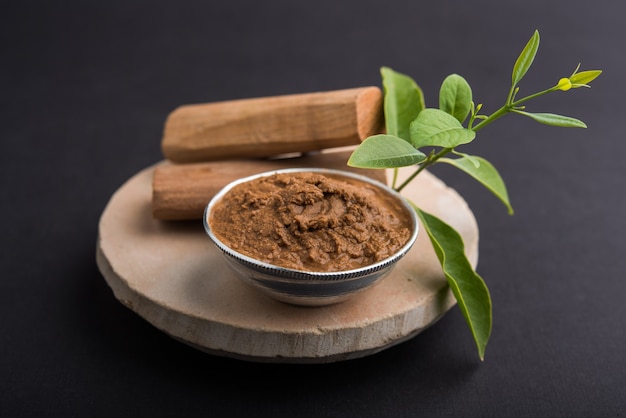 Ayurvedic Chandan or sandalwood paste in silver bowl with sticksand leaves placed over sahanor sahana or circular stone base for creating paste