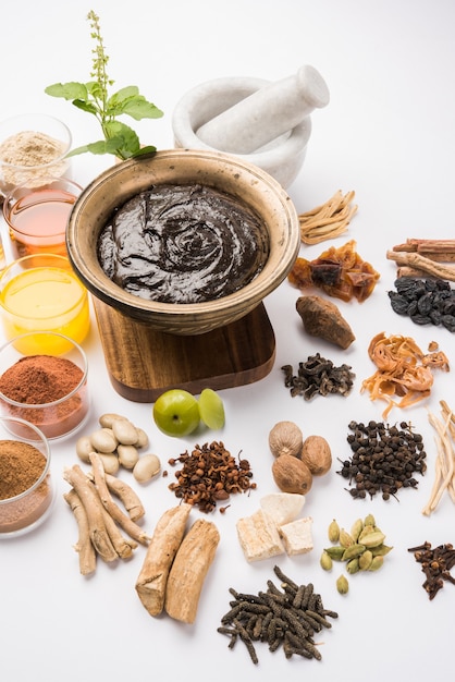 Ayurvedic Chyawanprash는 강력한 면역 강화제 또는 자연 건강 보조제입니다. 변덕스러운 배경 위에 재료와 함께 골동품 그릇에 제공, 선택적 초점