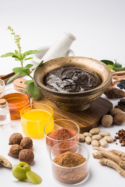 Ayurvedic Chyawanprash는 강력한 면역 강화제 또는 자연 건강 보조제입니다. 변덕스러운 배경 위에 재료와 함께 골동품 그릇에 제공, 선택적 초점