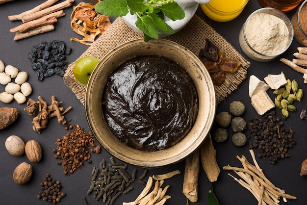 Ayurvedic Chyawanprash는 강력한 면역 강화제 또는 자연 건강 보조제입니다. 변덕스러운 배경 위에 재료와 함께 골동품 그릇에 제공, 선택적 초점