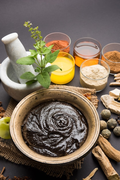 Ayurvedic Chyawanprash는 강력한 면역 강화제 또는 자연 건강 보조제입니다. 변덕스러운 배경 위에 재료와 함께 골동품 그릇에 제공, 선택적 초점