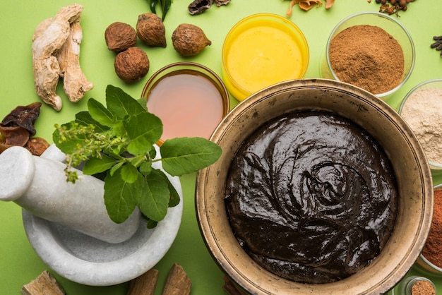 Ayurvedic Chyawanprash는 강력한 면역 강화제 또는 자연 건강 보조제입니다. 변덕스러운 배경 위에 재료와 함께 골동품 그릇에 제공, 선택적 초점