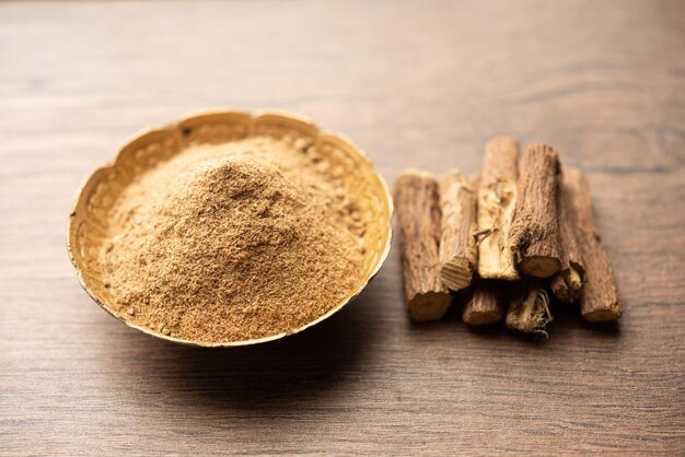 Photo ayurvedic mulethi or liquorice root stick or jeshthamadh powder served in a bowl over moody background