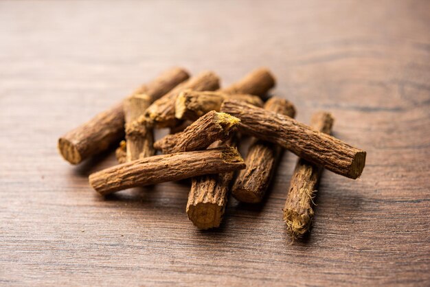 아유르베다 무레티 (Ayurvedic Mulethi) 또는 레코리스 뿌리 스틱 (Licorice root stick) 또는 제슈타마드 파우더 (jeshthamadh powder) 는 분위기적인 배경 위에 그으로 제공됩니다.