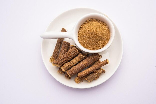 아유르베다 무레티 (Ayurvedic Mulethi) 또는 레코리스 뿌리 스틱 (Licorice root stick) 또는 제슈타마드 파우더 (jeshthamadh powder) 는 분위기적인 배경 위에 그으로 제공됩니다.