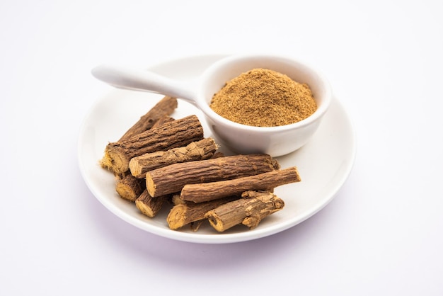 Photo ayurvedic mulethi or liquorice root stick or jeshthamadh powder served in a bowl over moody background