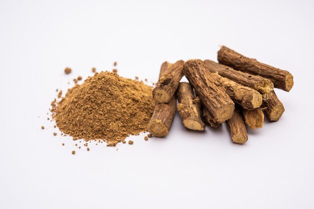 Photo ayurvedic mulethi or liquorice root stick or jeshthamadh powder served in a bowl over moody background