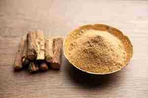 Photo ayurvedic mulethi or liquorice root stick or jeshthamadh powder served in a bowl over moody background