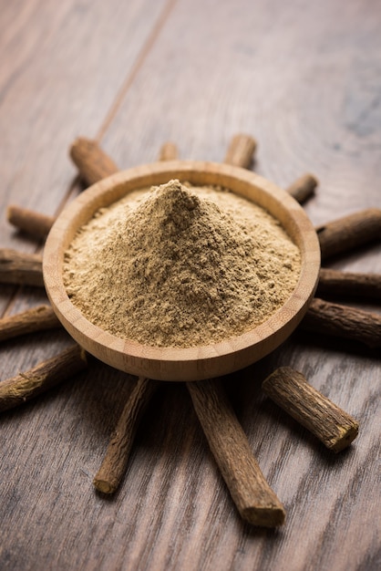 Photo ayurvedic mulethi or liquorice root stick or jeshthamadh powder served in a bowl over moody background