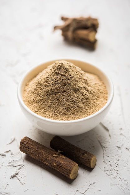 Photo ayurvedic mulethi or liquorice root stick or jeshthamadh powder served in a bowl over moody background