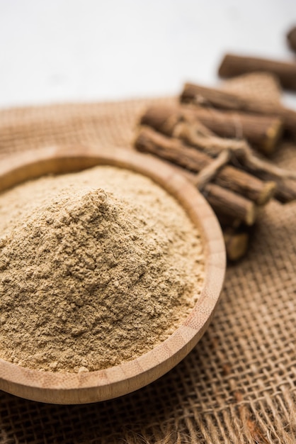 Ayurvedic Mulethi or Liquorice root stick or jeshthamadh powder served in a bowl over moody background